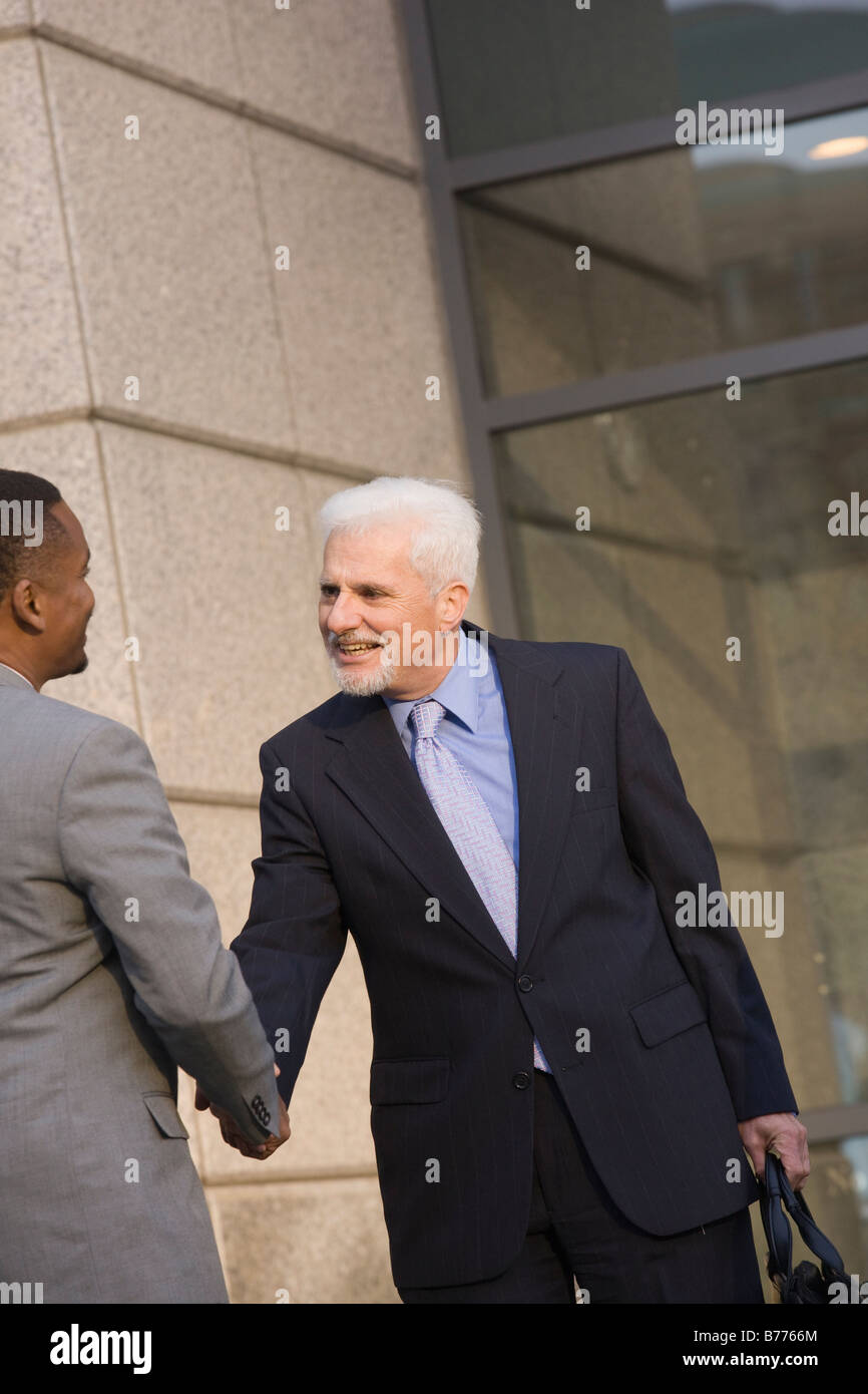 Two businessmen shaking hands in front of office building Stock Photo ...