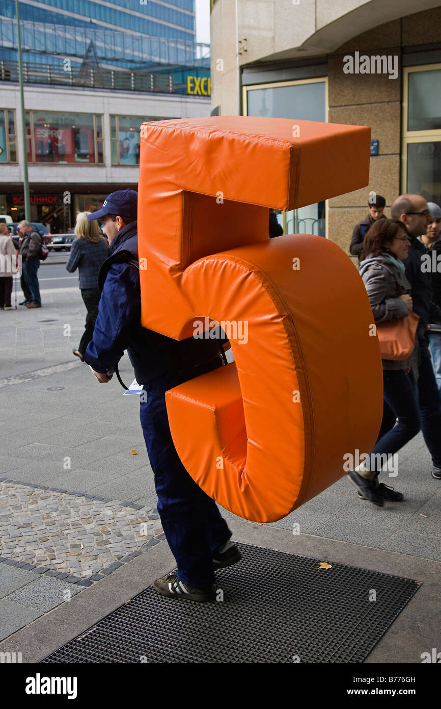 Man carrying a big orange 5 on his back, Kurfuerstendamm, Berlin, Germany, Europe Stock Photo