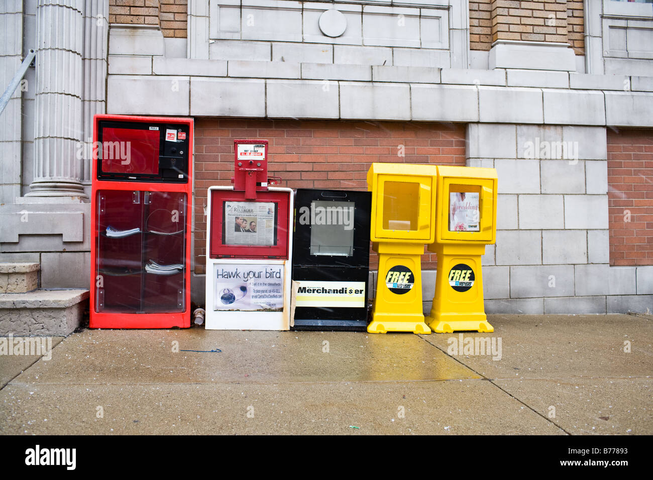 A row of newspaper machines sit along a sidewalk Stock Photo