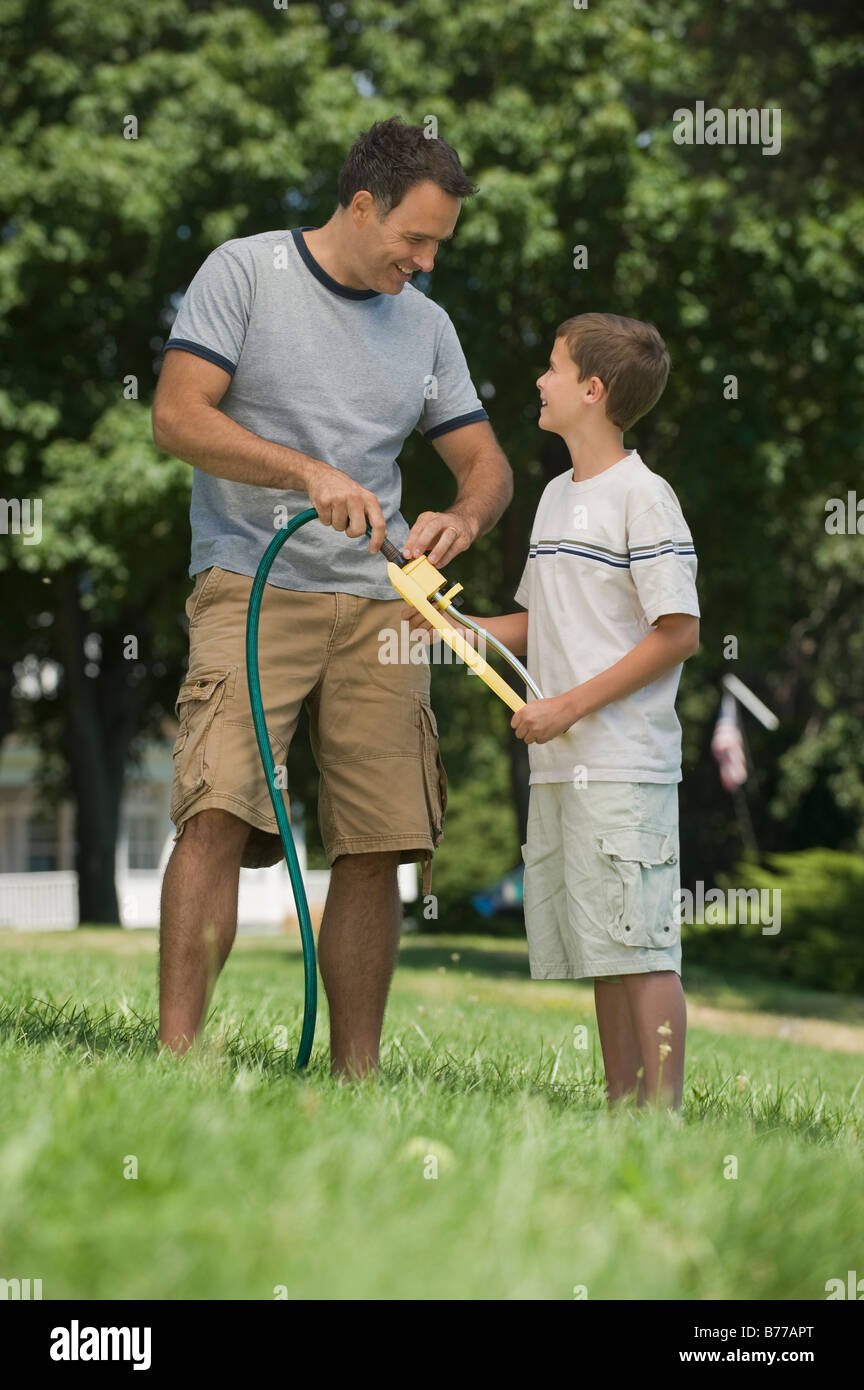 Boy helping father sprinkler backyard Stock Photo