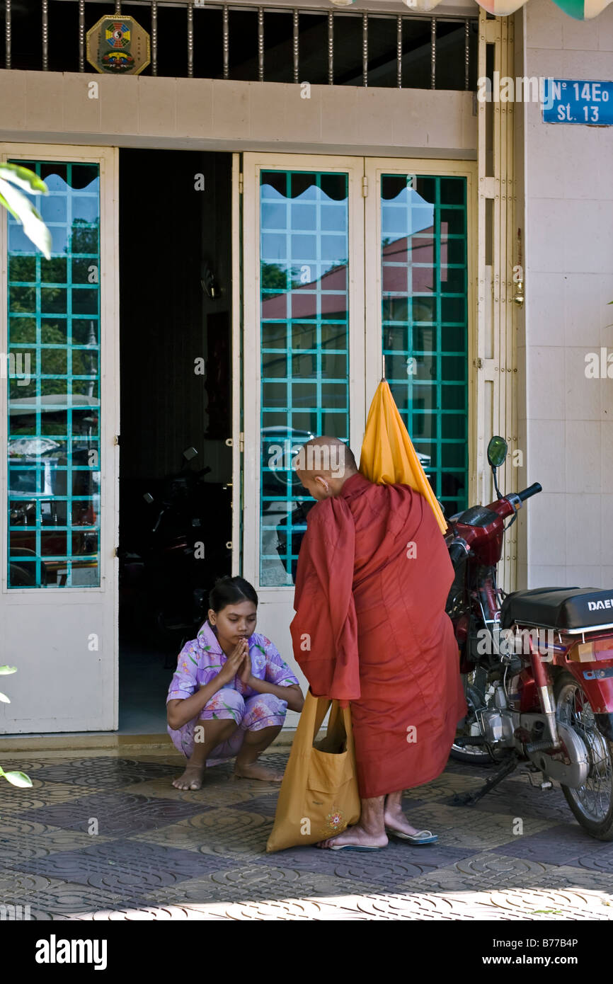 Child praying. A young Cambodian Buddhist child paying respect and praying to a visiting monk outside her home. Cambodia S. E. Asia. Real image Stock Photo