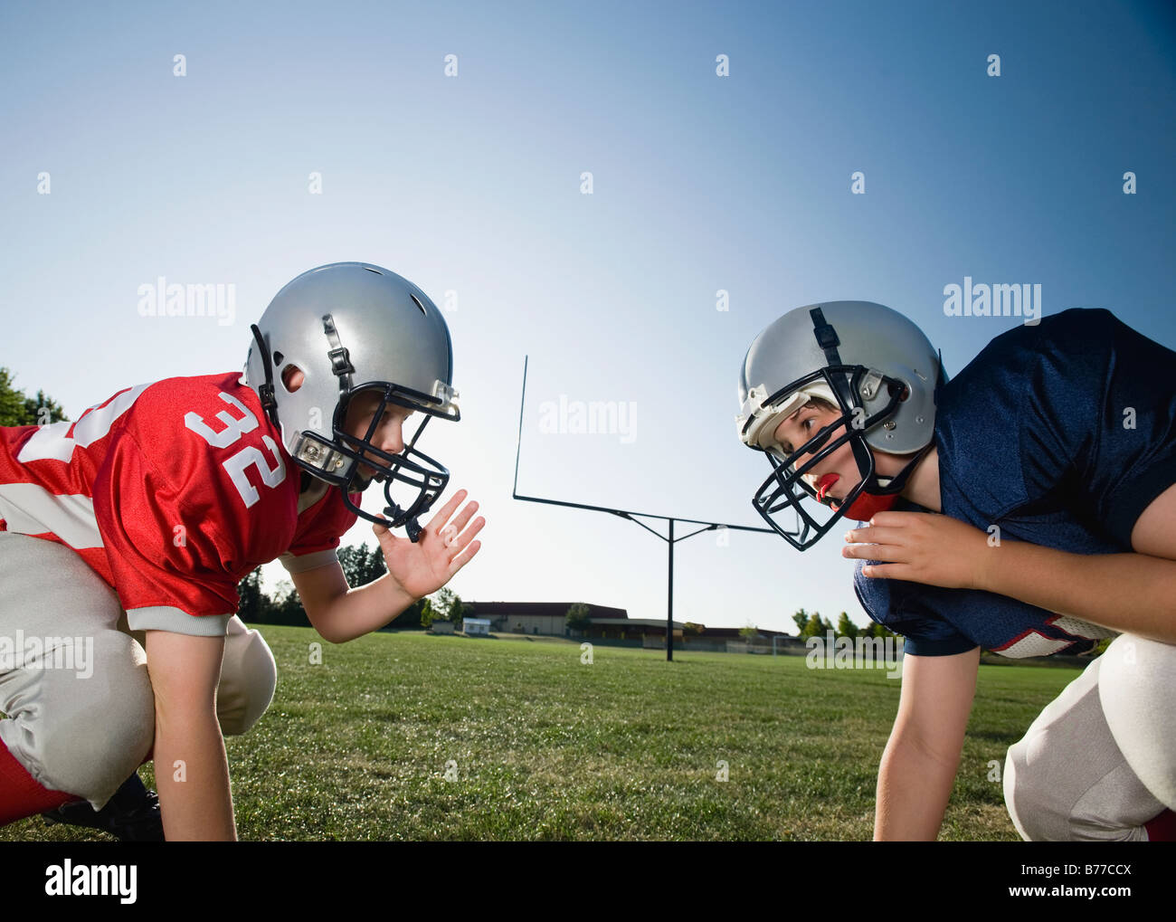 Opposing football players facing line of scrimmage Stock Photo