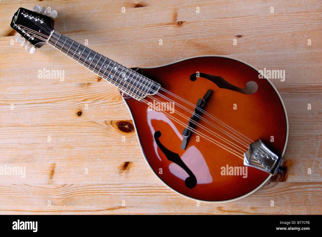 A fine A-style f-hole handmade mandolin with solid carved spruce top on a worn pine wood tabletop Stock Photo