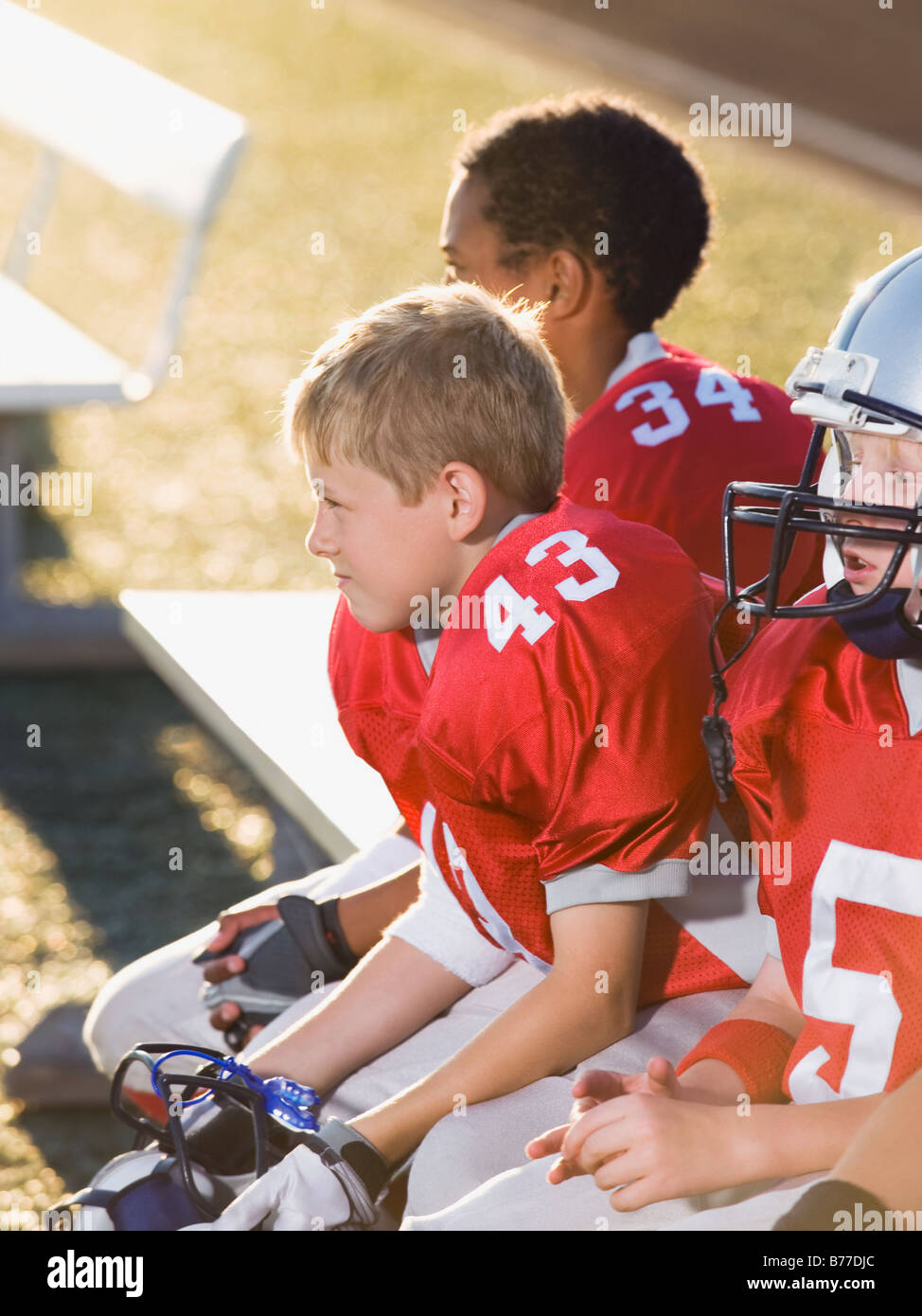 Football players sitting on bench Stock Photo