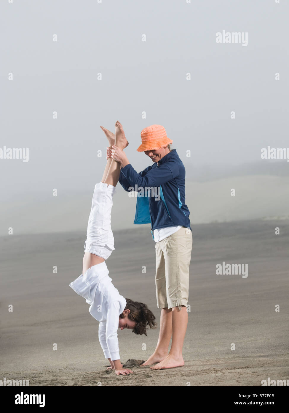 Mother holding daughter upside down on beach Stock Photo Alamy