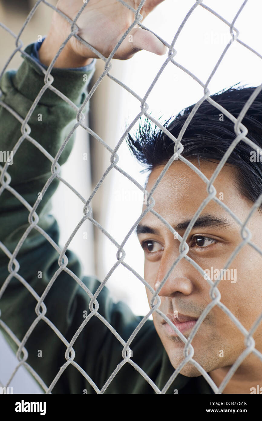 Close up of young man leaning against chain-link fence Stock Photo - Alamy