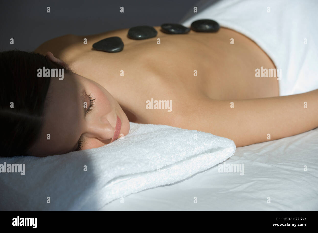 Woman laying on massage table warm stones on back Stock Photo