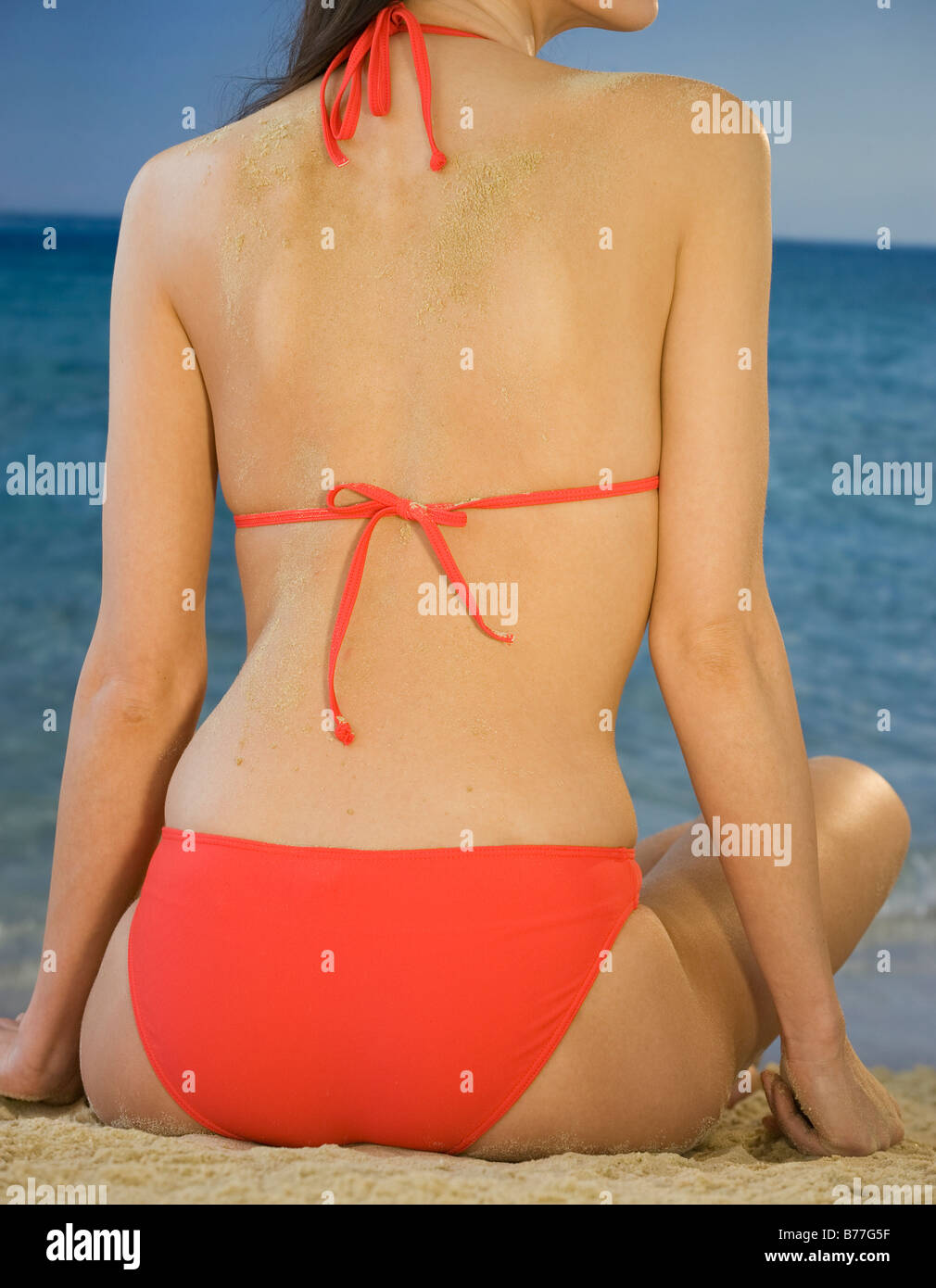 Rear view of woman bikini sitting on beach, close up Stock Photo - Alamy