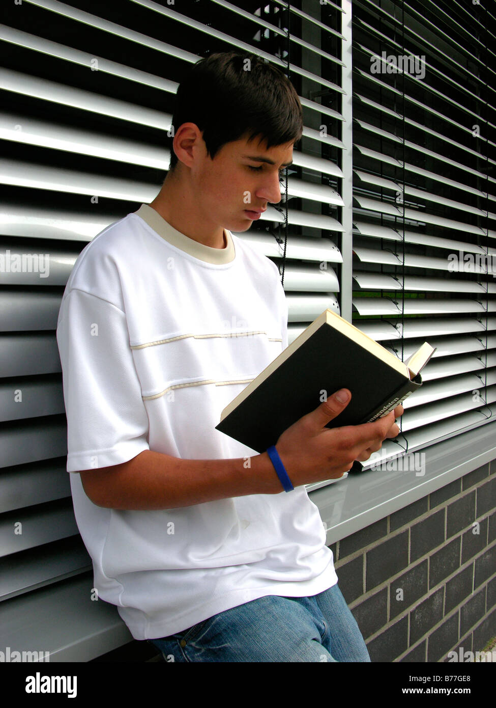 16-year-old pupil reading a book during the break Stock Photo
