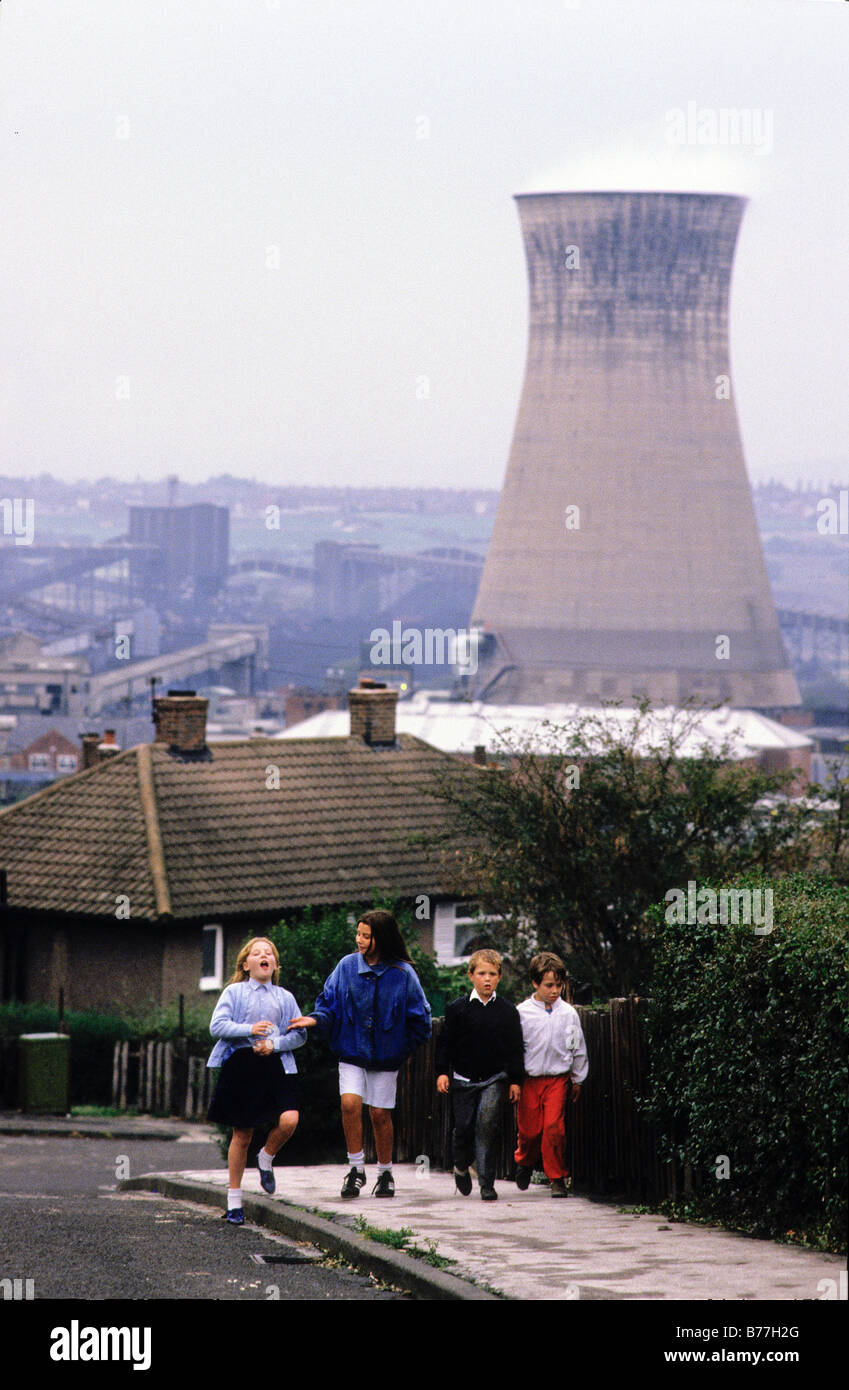 'Grimethorpe, UK. Four miner's children walk along the street with a power station situated in the background. Stock Photo