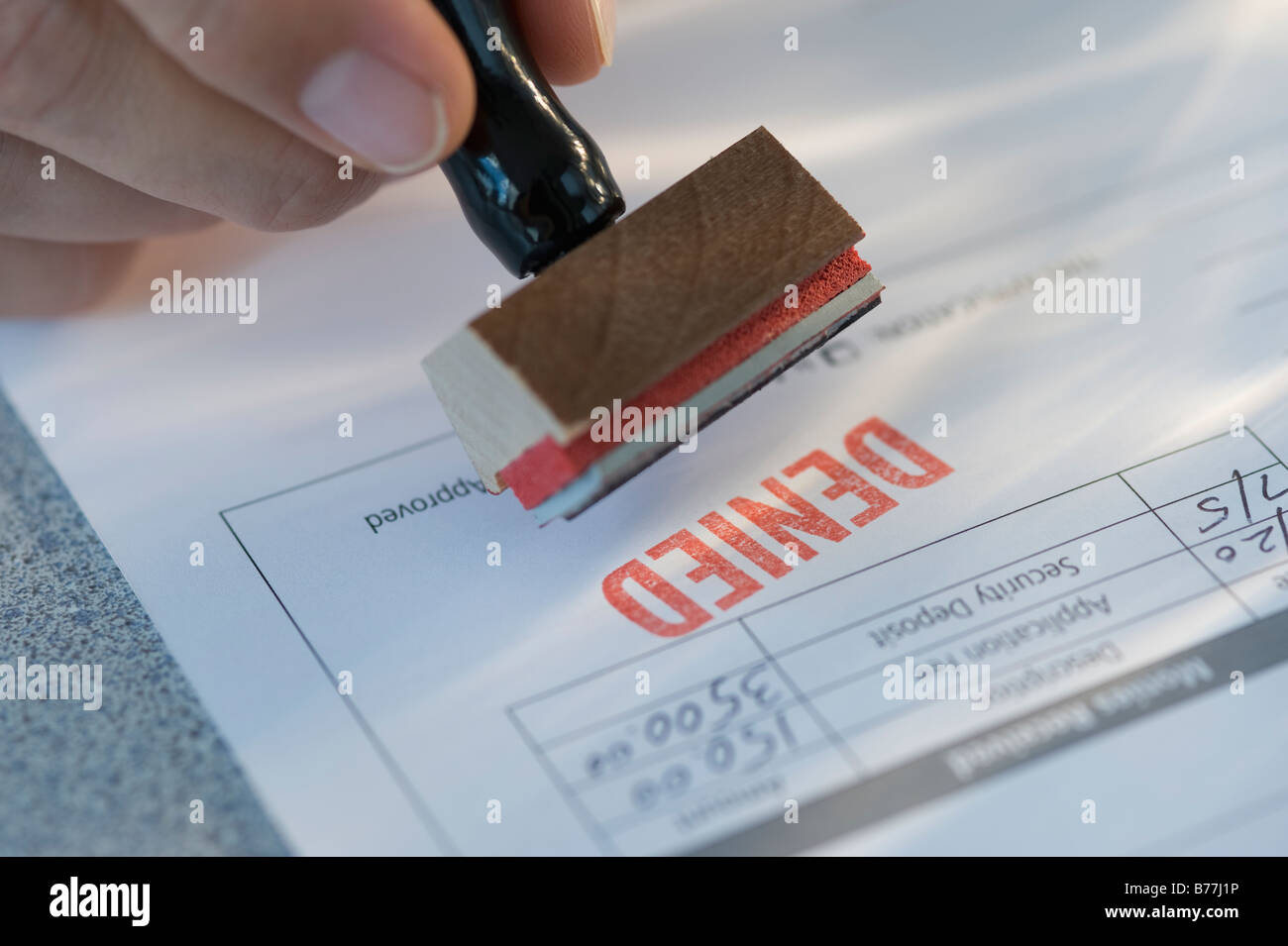 Man stamping “denied” on mortgage application Stock Photo