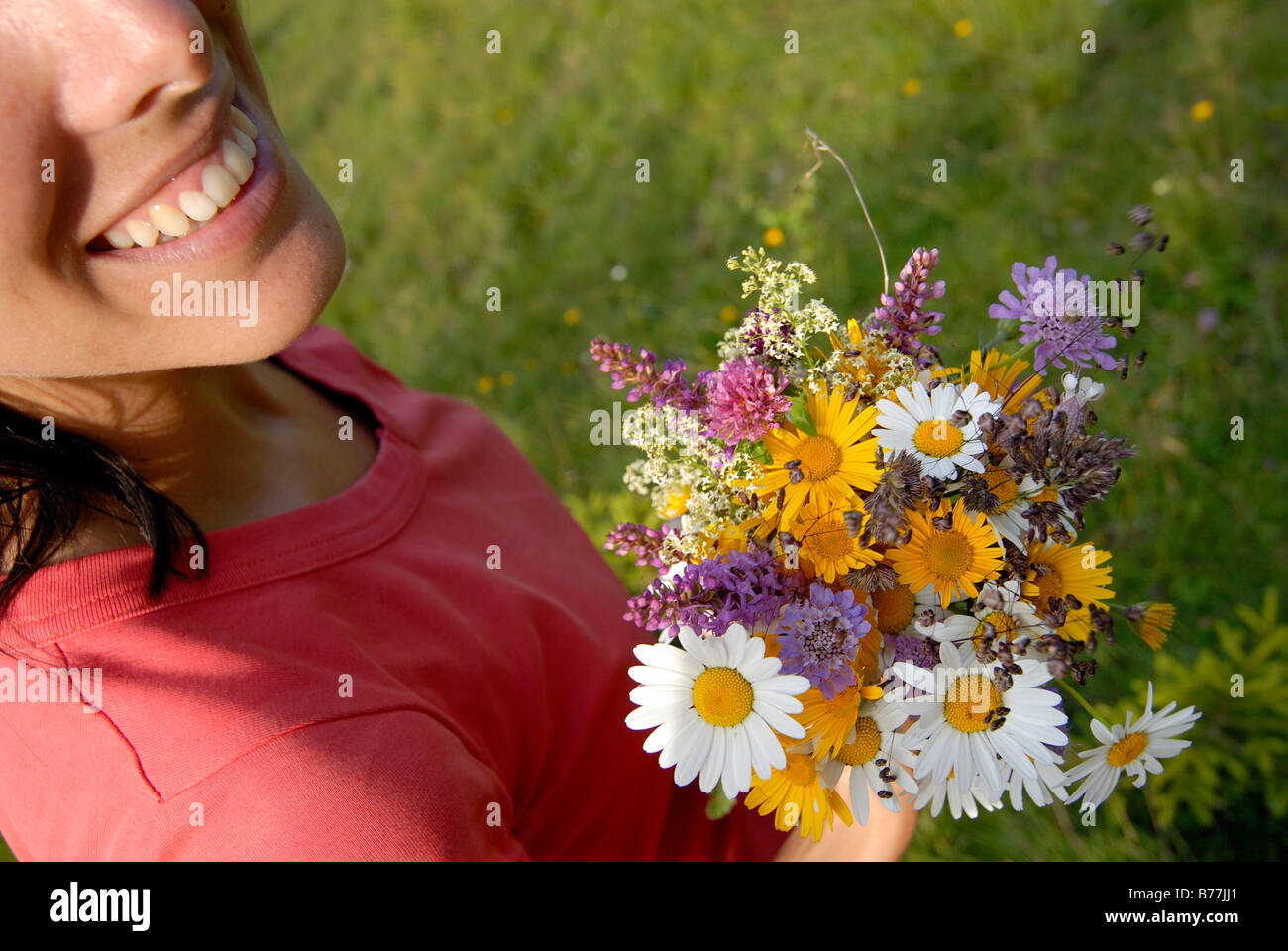 Smiling young woman holding a bunch of flowers, Tyrol, Austria, Europe Stock Photo