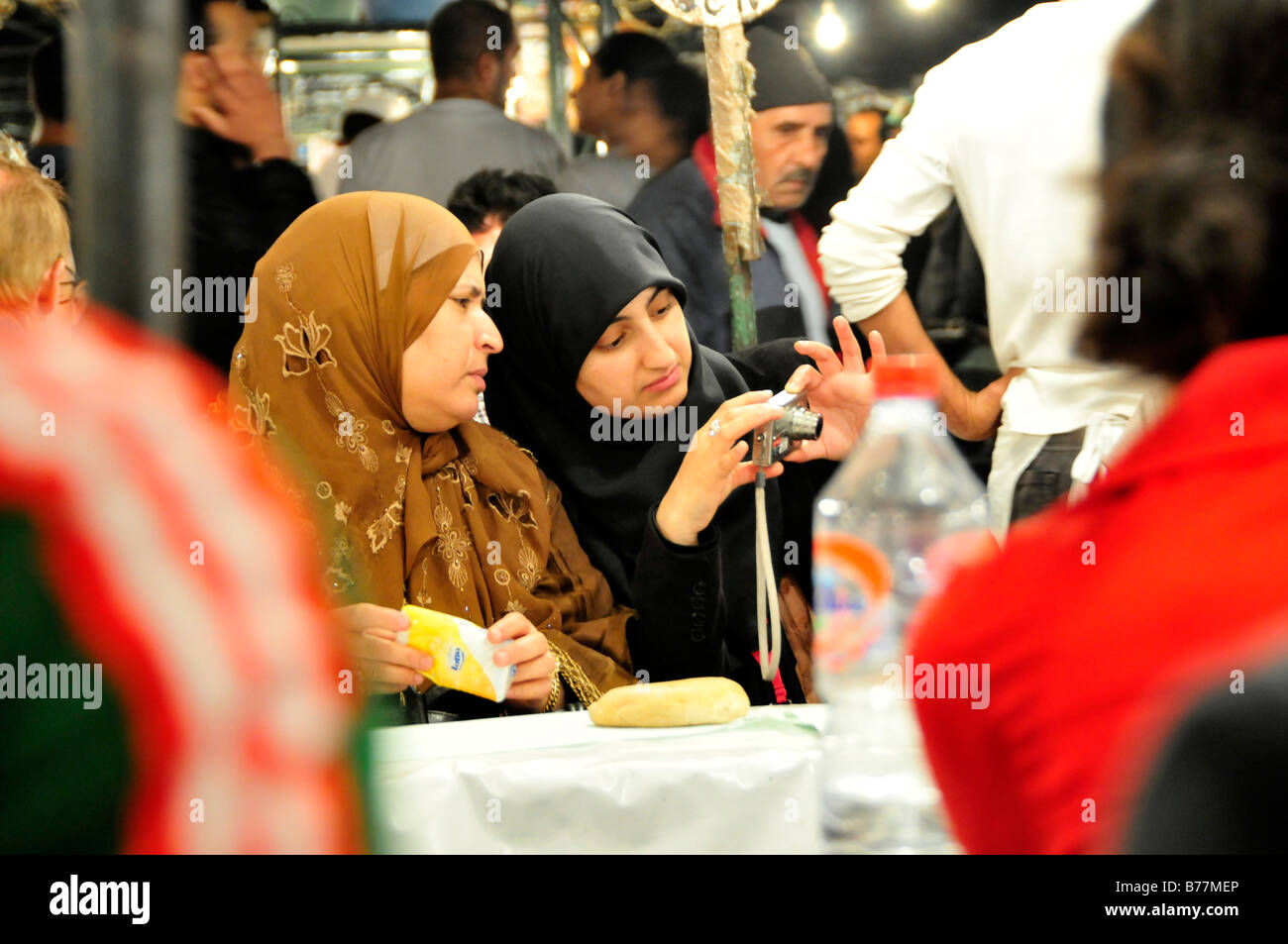 Two veiled women with a digital camera in a restaurant in the Place Djemma el-Fna, Square of the hanged, imposter square, Marra Stock Photo