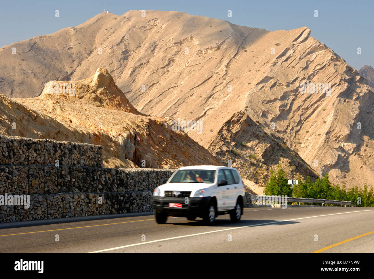 Vehicle, modern street cutting through a sparse mountain landscape, Sultanate of Oman, Middle East Stock Photo