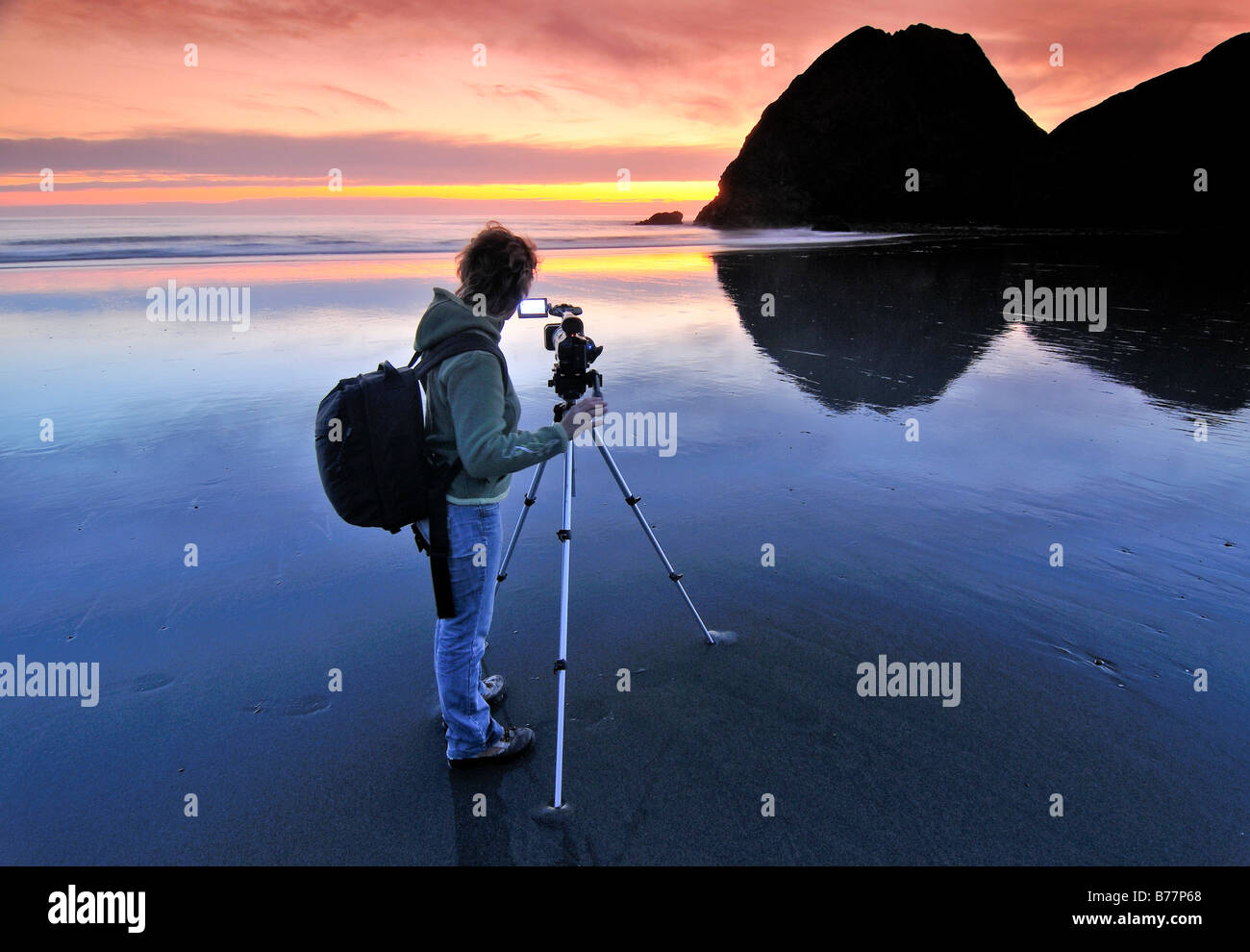 Camerawoman with movie camera filming sunset with a tripod at Meyers Creek Beach, Pistol River State Park, Oregon Coast, Oregon Stock Photo