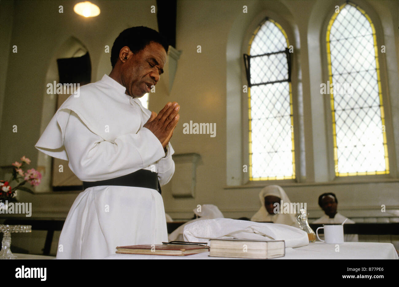 Brotherhood Of The Cross And Star, Moss Side Manchester, UK, 1993 A priest clasps his hands in prayer during a baptism service. Stock Photo