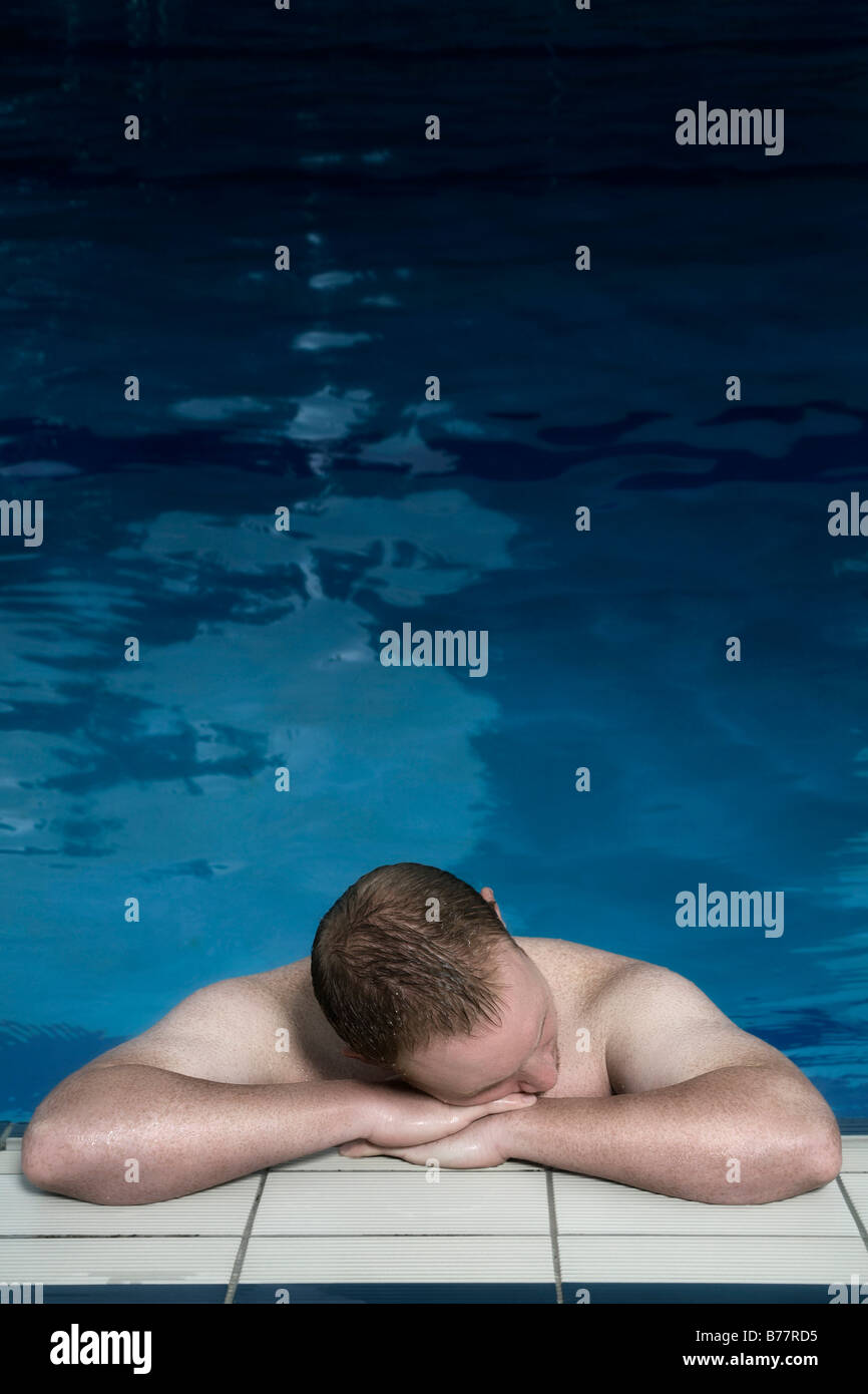 Young man leaning on the edge of a swimming pool Stock Photo