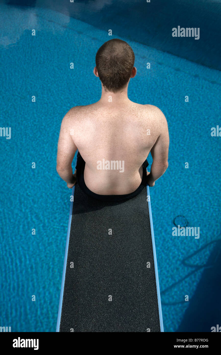 Young man sitting on a diving board Stock Photo