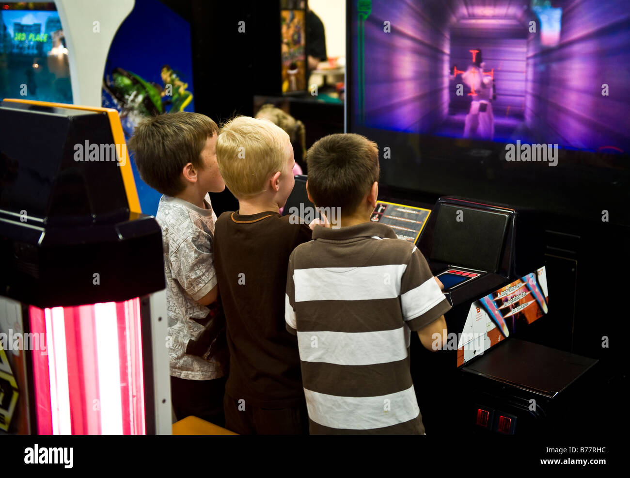 Boys playing a video game in an arcade Stock Photo