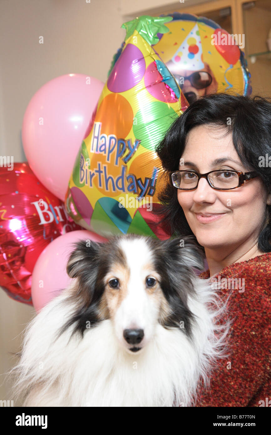 a woman holding a dog at his birthday party Stock Photo