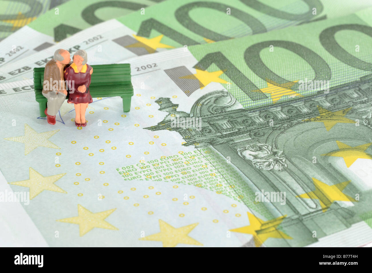 Figures of two seniors sitting on Euro banknotes, symbolic image for pension plan, retirement Stock Photo
