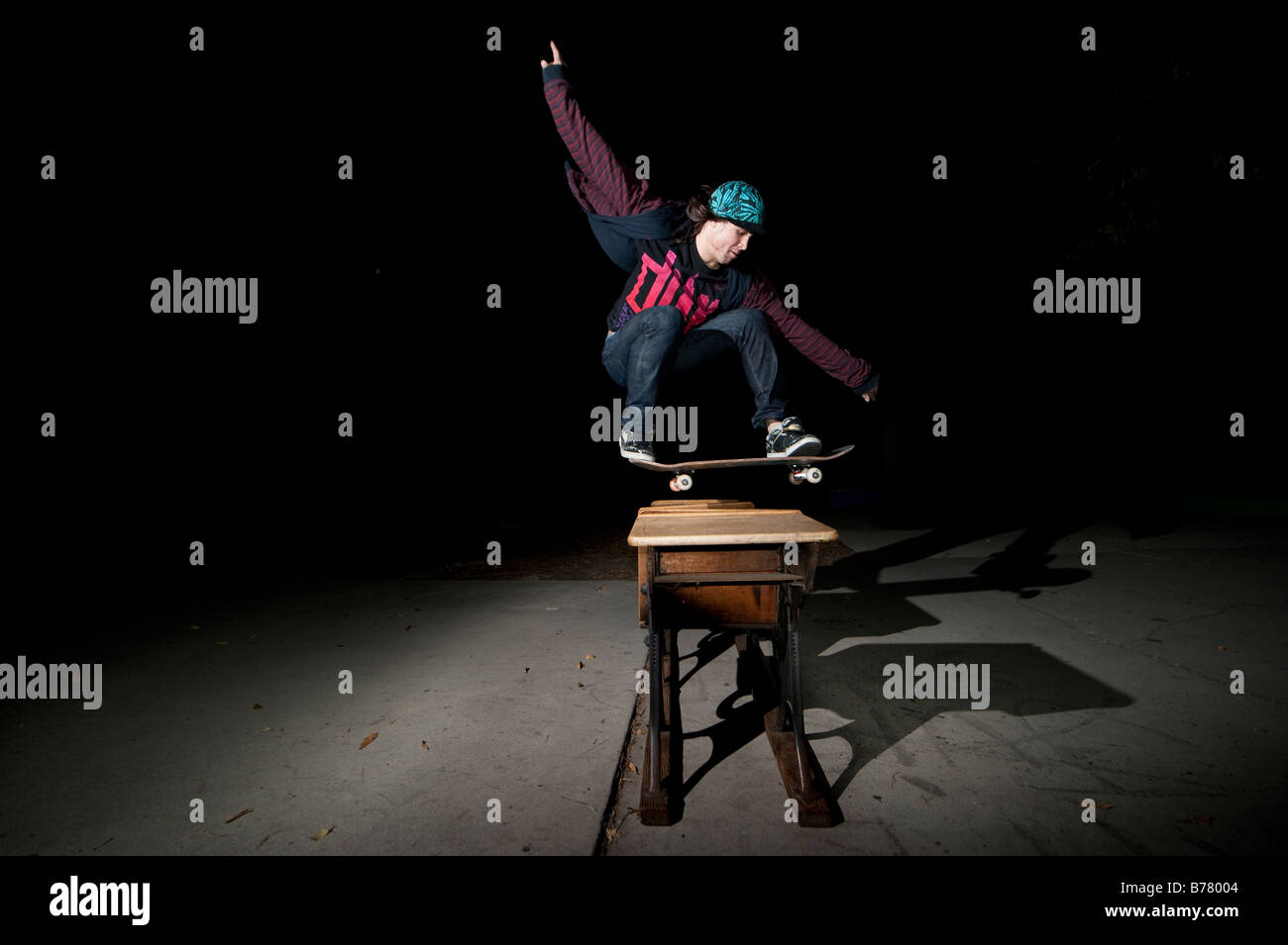 Skateboarder jumping over desks Stock Photo