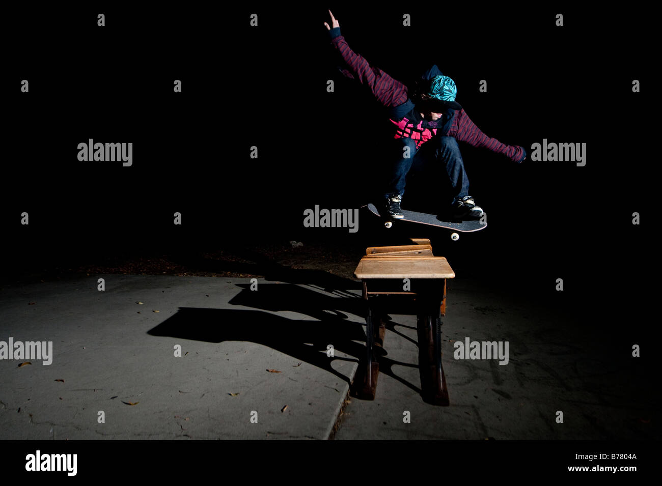 Skateboarder jumping over desks Stock Photo