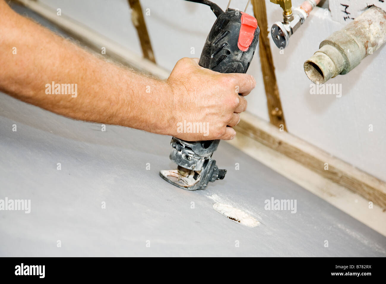 Contractor using a rotary saw to cut holes in drywall for the plumbing pipes Authentic and