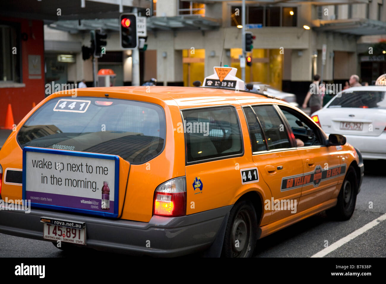 rear view of an orange coloured brisbane taxi at red traffic lights