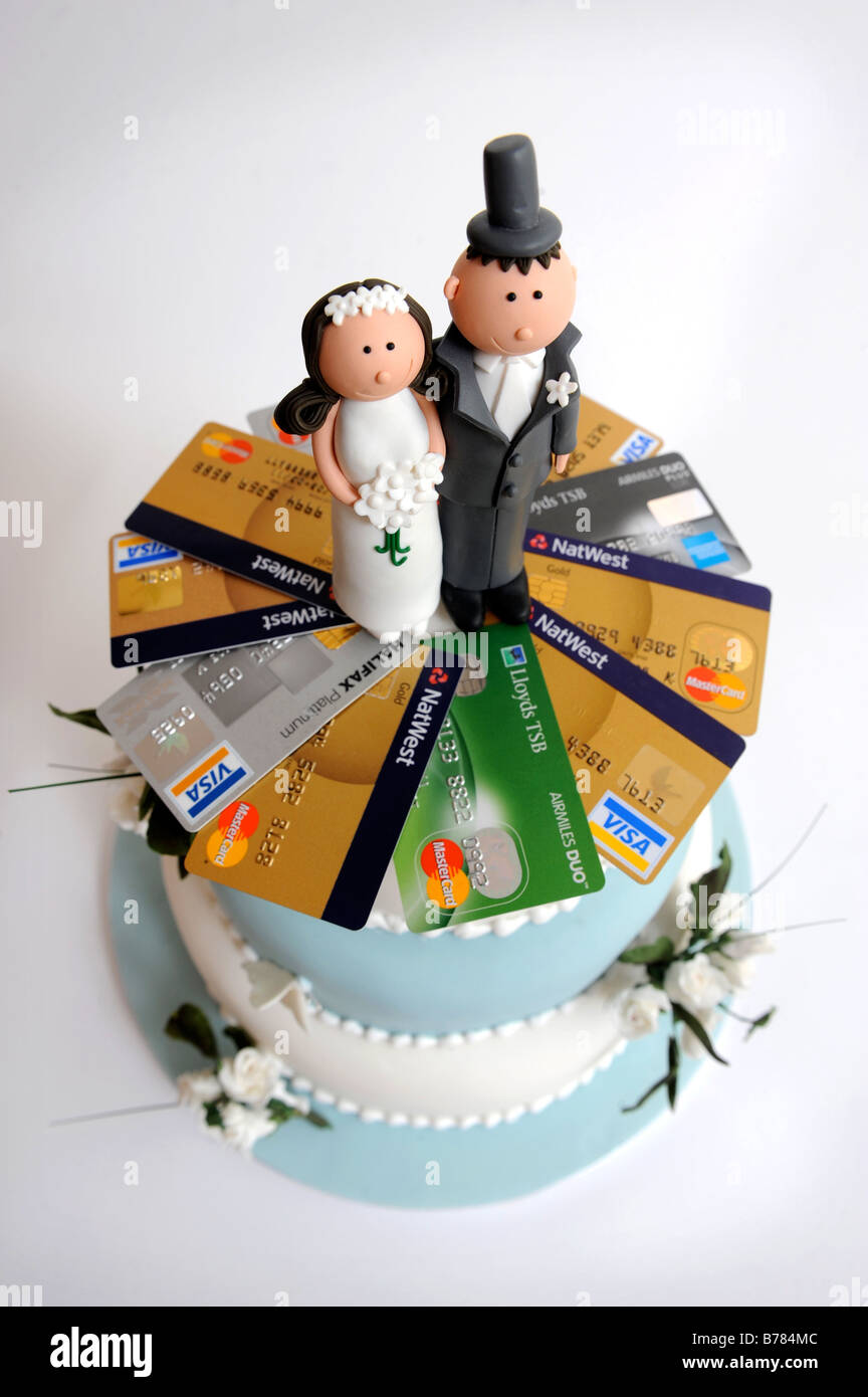 A THREE TIER WEDDING CAKE WITH DECORATIVE FLOWERS AND COMIC BRIDE AND GROOM FIGURES ALSO DECORATED BY CREDIT CARDS Stock Photo