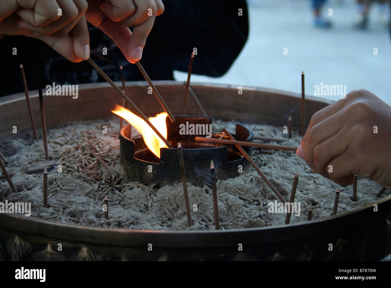 Three hands of school children lighting incense at the entrance to the Todai-ji temple, Japan. Stock Photo