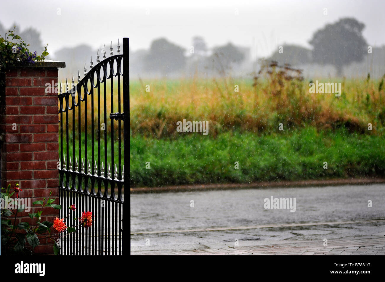 wrought iron garden entrance gate open in wet weather conditions Stock