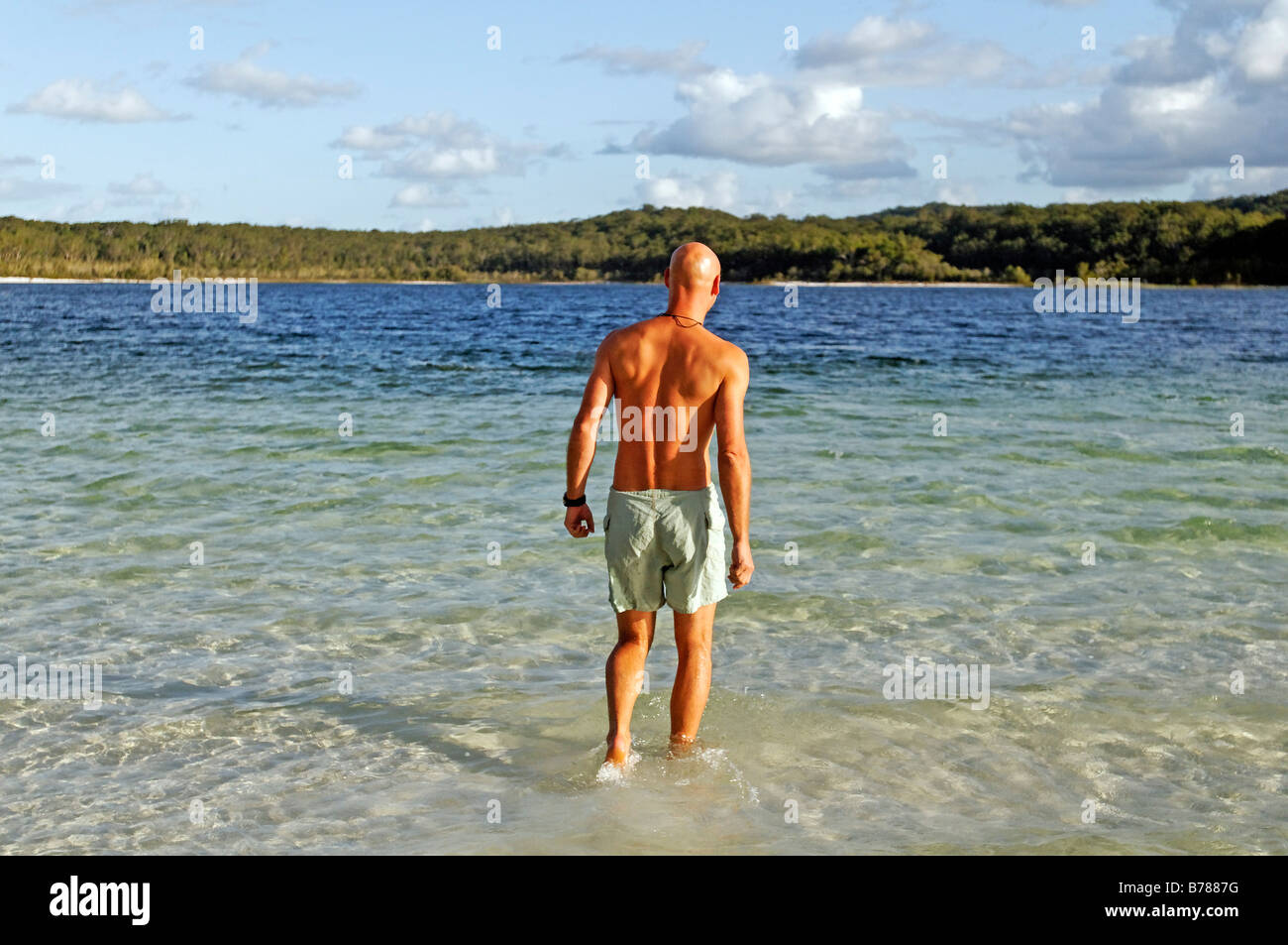 Young man walks into Lake McKenzie, Fraser Island, Queensland, Australia Stock Photo