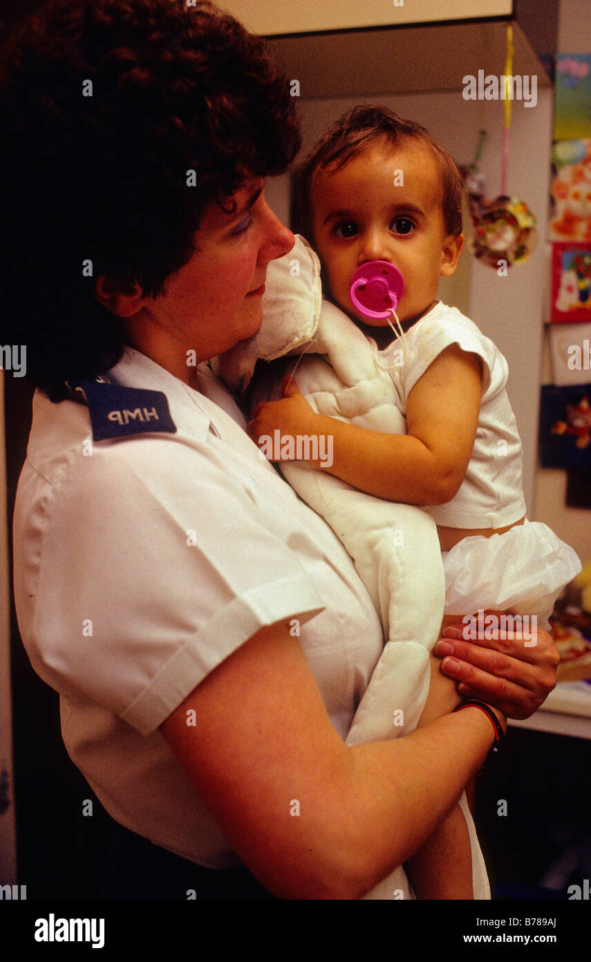 A prison officer holds the baby of a young inmate.' Stock Photo