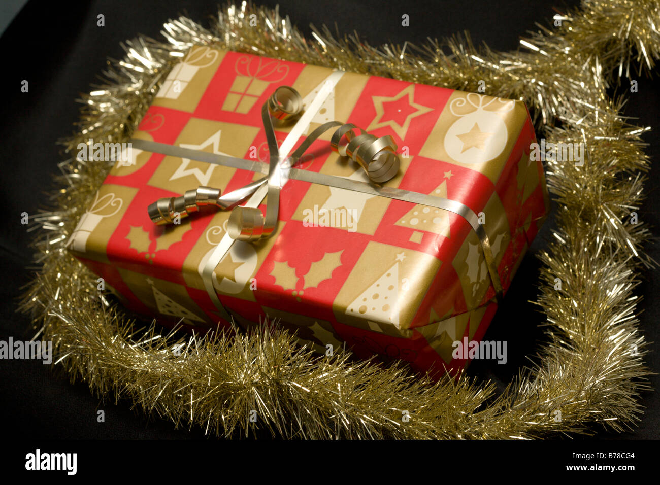 Christmas present in gold and red paper wrapped with a gold ribbon Stock Photo