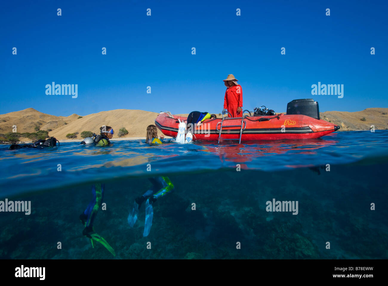 Divers ardously clamber on to the boat after diving, Indonesia, South Asia Stock Photo