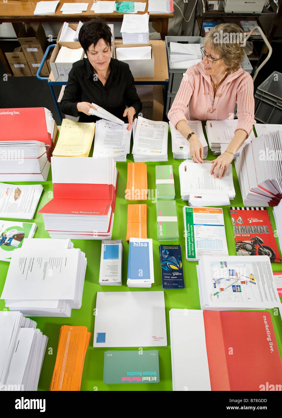 Two female employees of the logistics department of Messe Schweiz sorting and arranging brochures and papers for dispatch Stock Photo