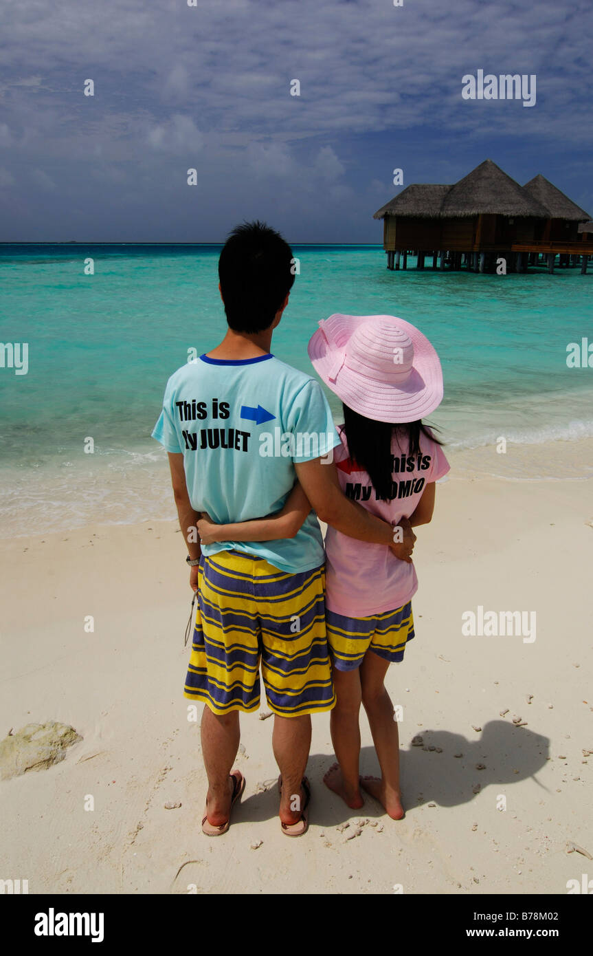 Japanese honeymooners on the beach wearing Romeo and Juliet T-shirts in Baros Resort, The Maldives, Indian Ocean Stock Photo