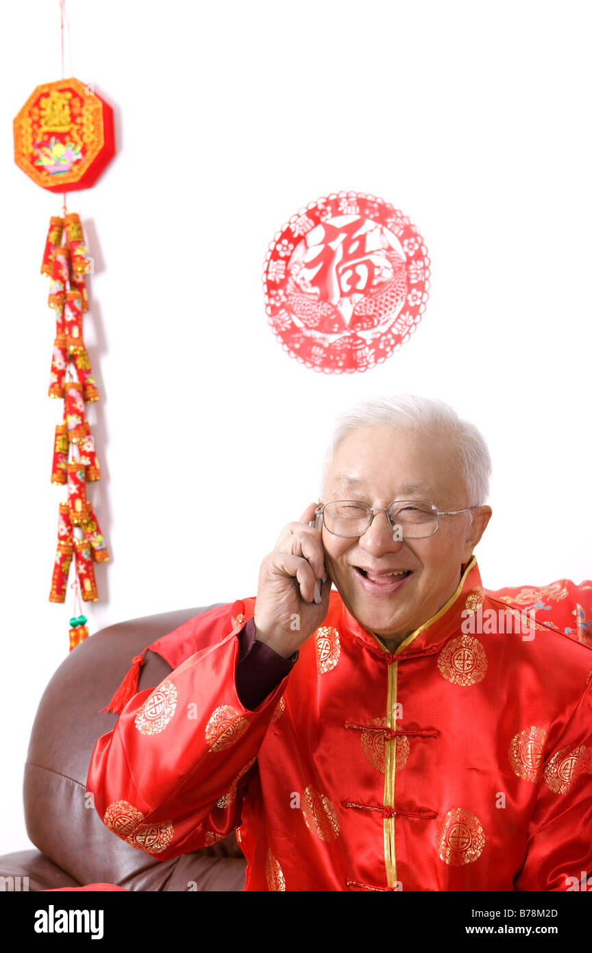Elderly man in traditional clothes smiling happily, on the phone Stock Photo