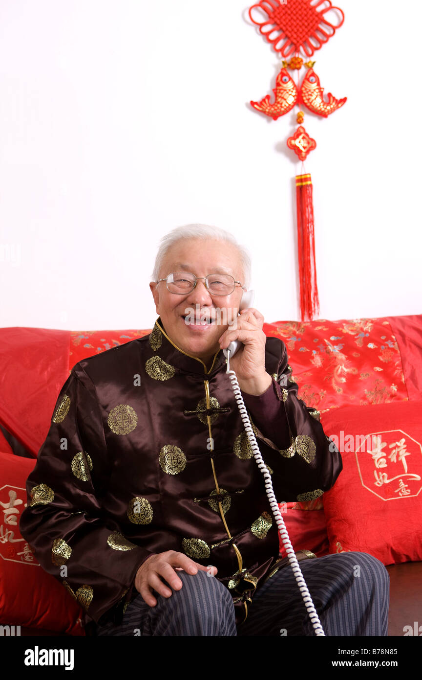 Senior man in traditional clothes holding the telephone and smiling at the camera Stock Photo