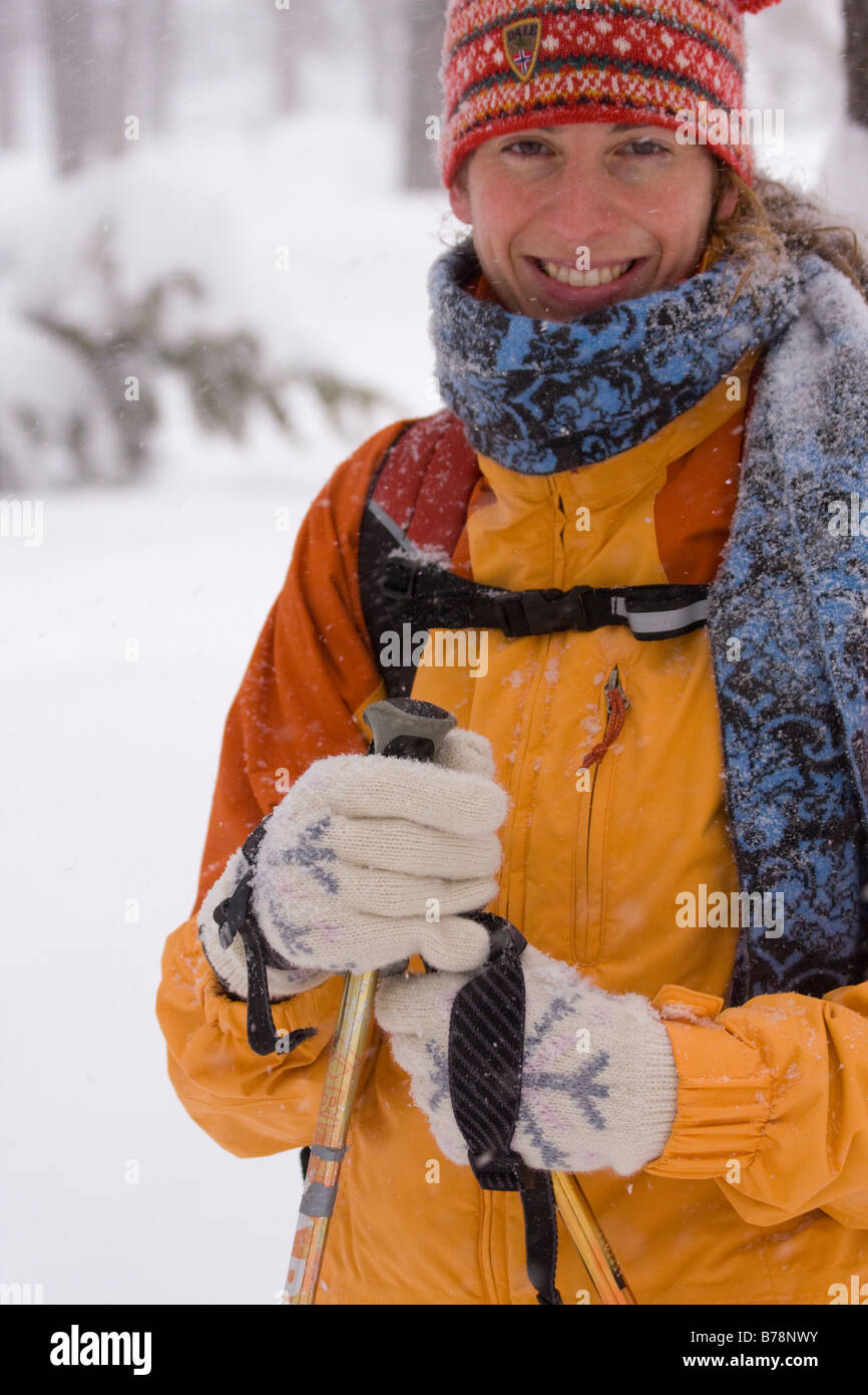 A woman snowshoeing and smiling in a forest during a snow storm storm