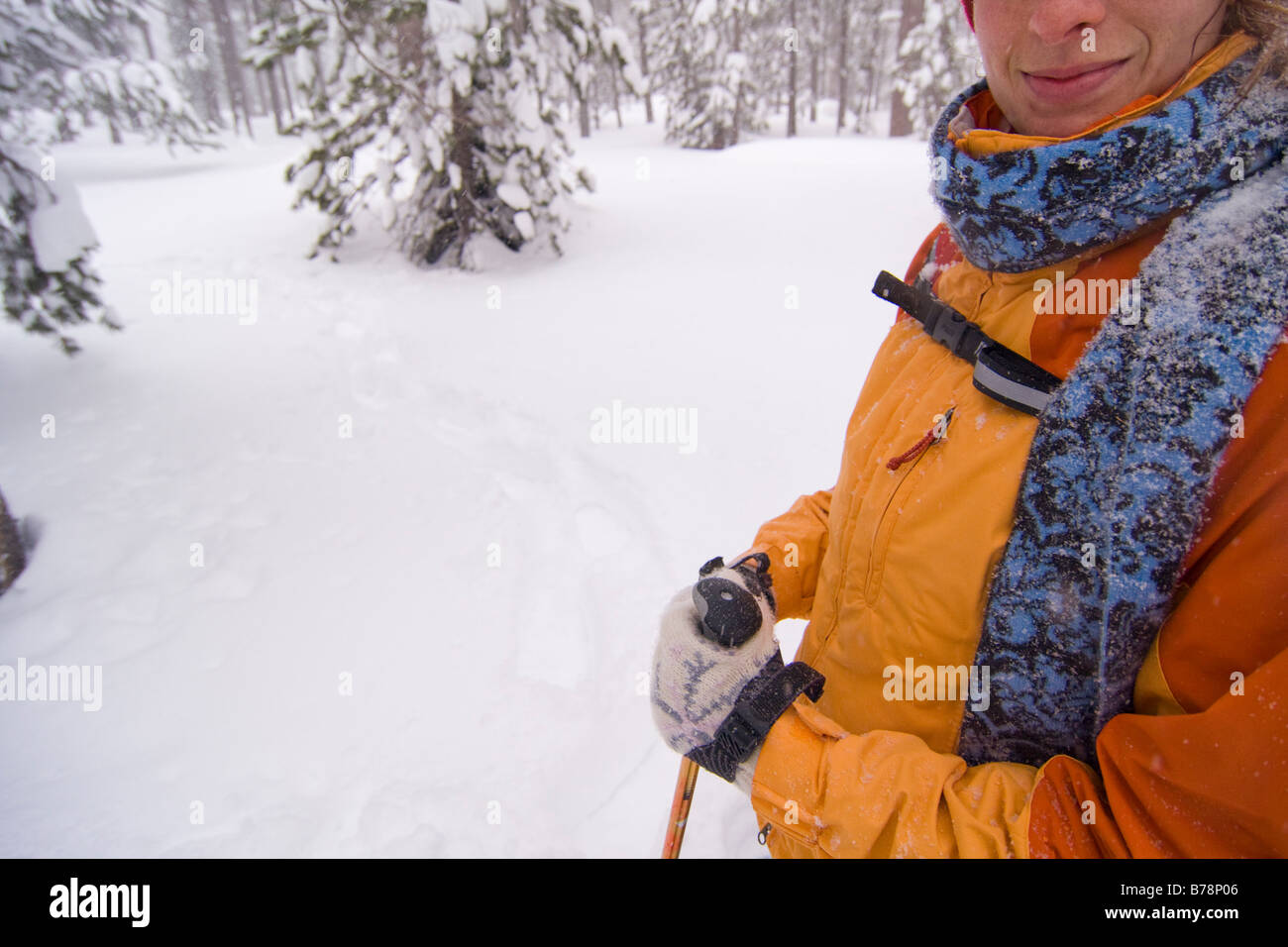 A woman snowshoeing and smiling in a forest during a snow storm storm