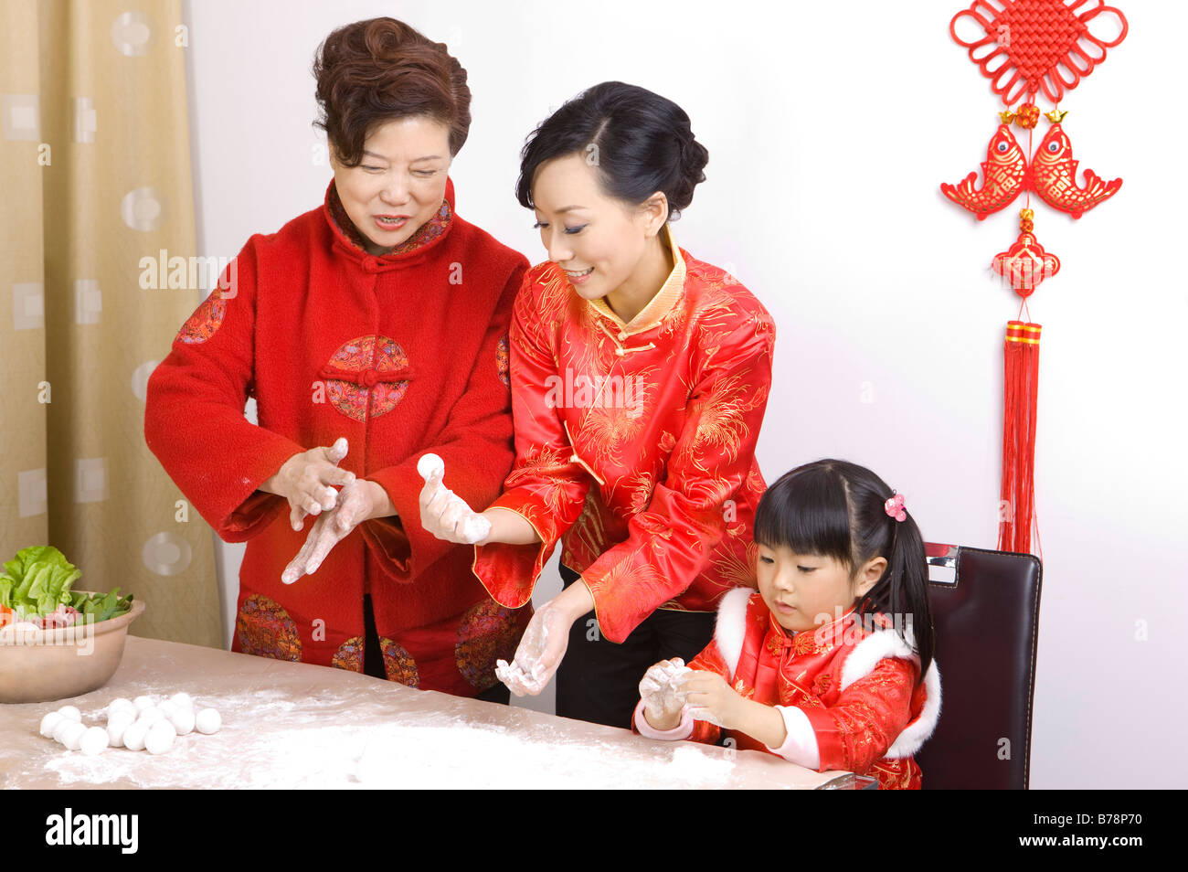 Two women and a little girl making stuffed dumplings together Stock Photo