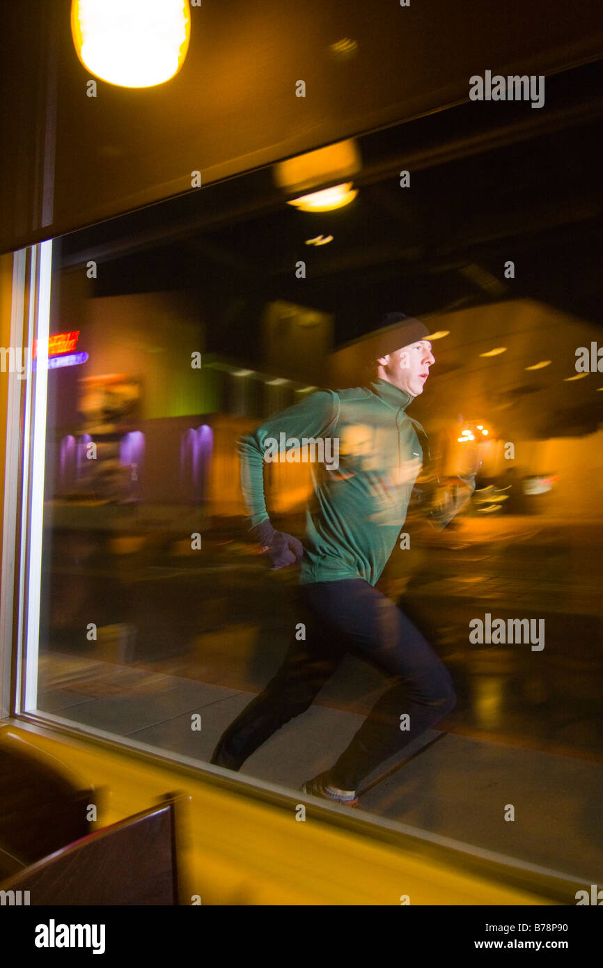 A man running along the road at night under the lights of Reno in Nevada Stock Photo
