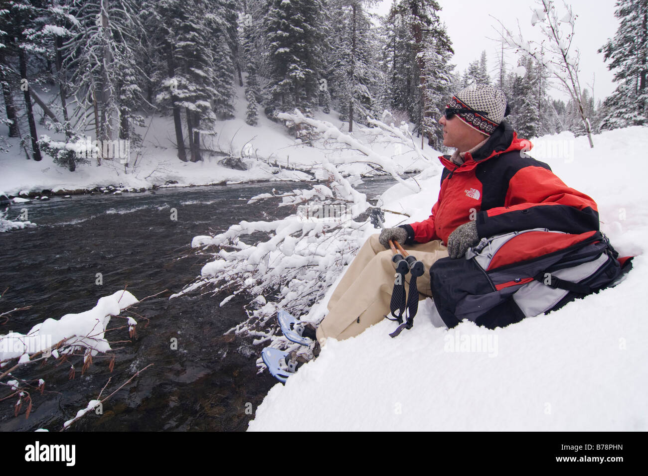 A man snow shoeing along the Truckee river while it snows in Truckee in California Stock Photo