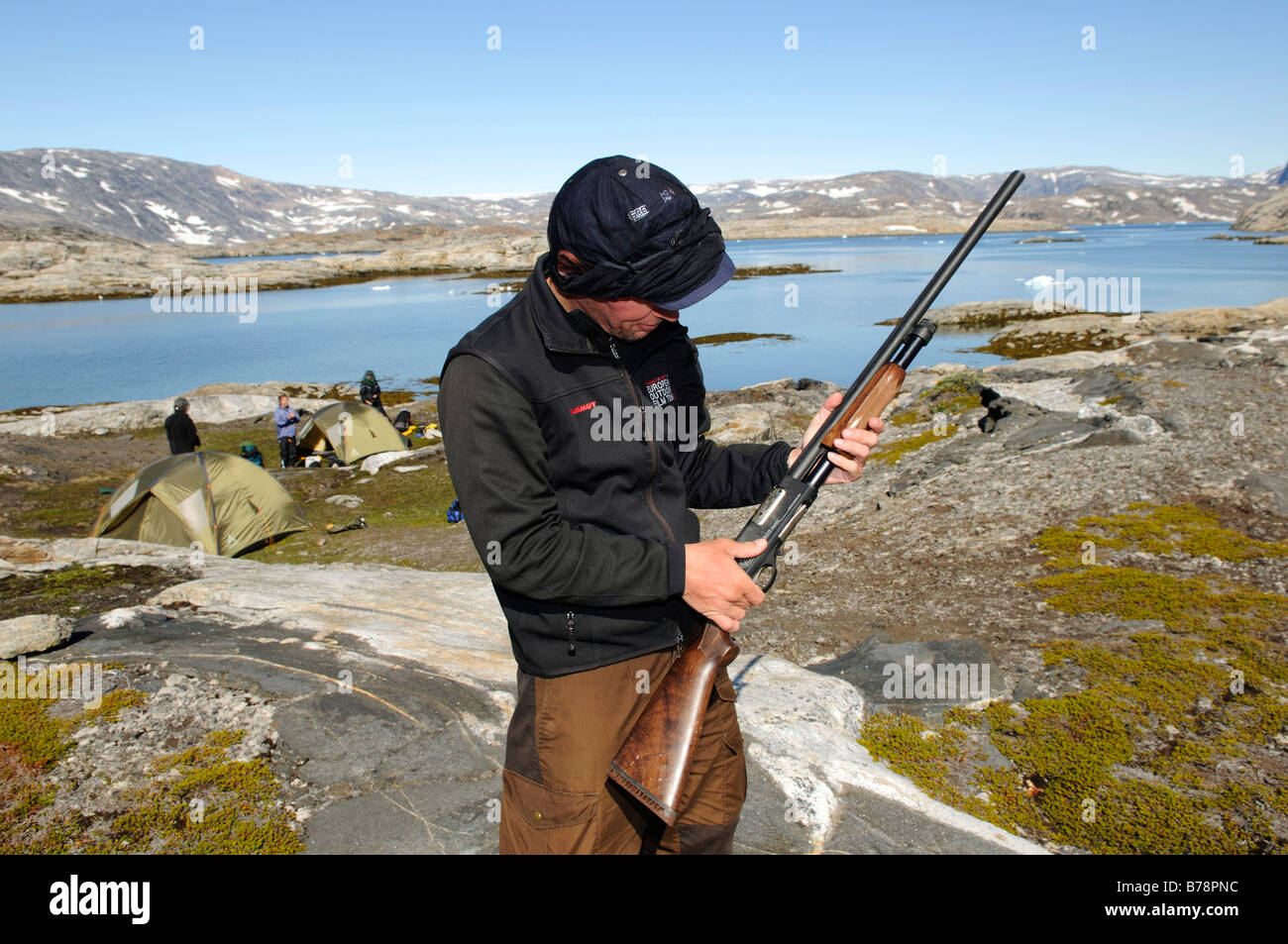 Trekker checking his shotgun for defence against polar bears, Ikasartivaq Fiord, East Greenland Stock Photo