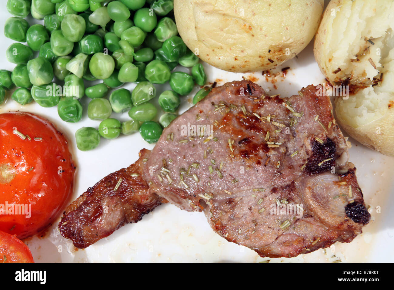 Lamb loin chop grilled with rosemary,baked potato,tomatoes and peas