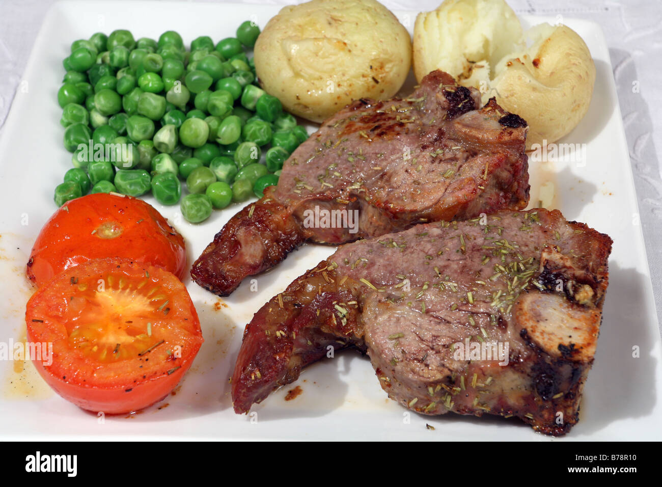 Grilled lamb chop with rosemary,potatoes,tomatoes,peas Stock Photo Alamy