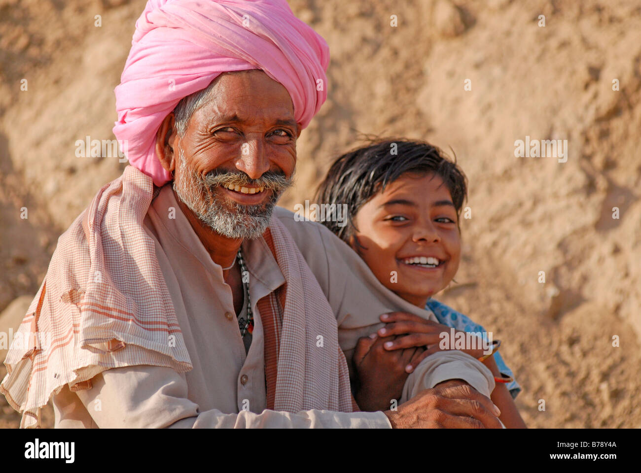 Man wearing a pink turban and a child, Ram Devra pilgrims festival, Ramdevra, Pokhran, Rajasthan, North India, Asia Stock Photo