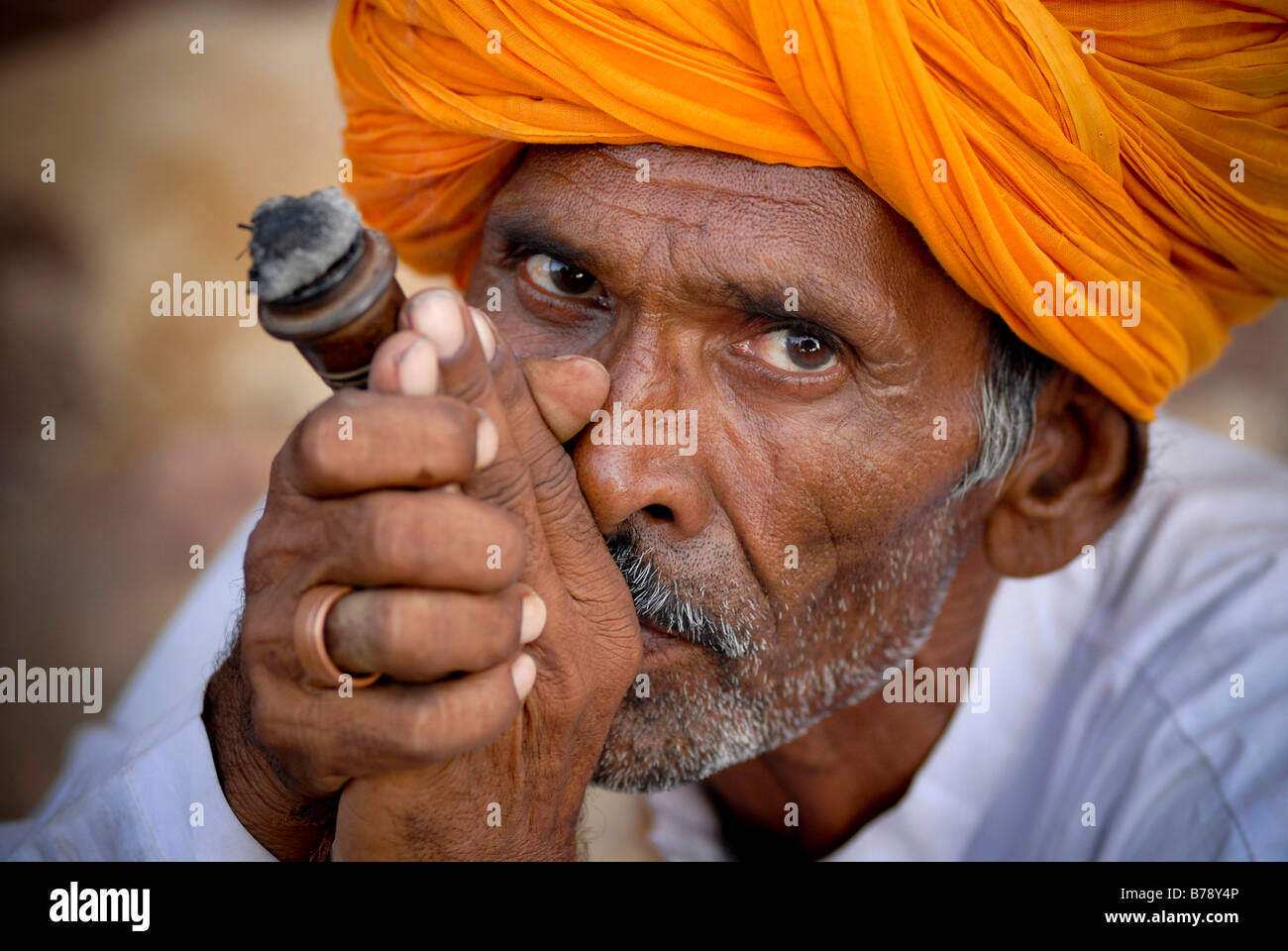 Man wearing orange turban, smoking chilam, Ram Devra pilgrims festival, Ramdevra, Pokhran, Rajasthan, North India, Asia Stock Photo